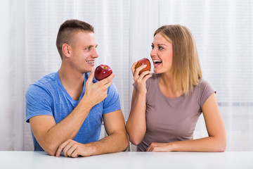 Young happy couple eating apple together.