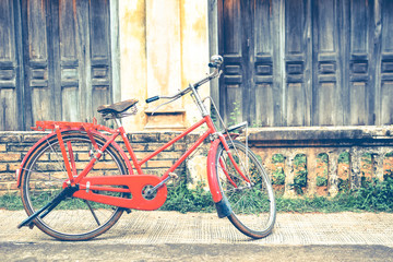 Fototapeta na wymiar Hipster red bicycle in old building walls background , color if vintage tone