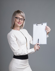 Portrait of beautiful young woman with phone and blank signboard, dressed in pin-up style. Caucasian blond model posing in retro fashion and vintage concept studio shoot, on grey background.