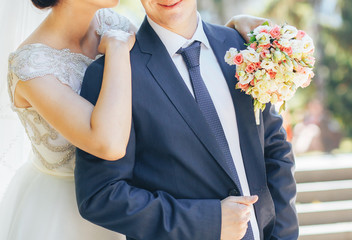 The bride and groom arm in arm stand together posing