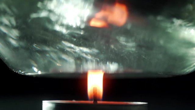 Chemical experiments with ignition of reagents: a glass flask with chemical fluid is held over the fire. The candle burns and heats the chemical reagent.A chemical flask over the fire.