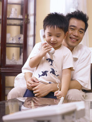 father and son enjoy making phone call