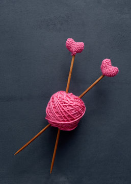 Pink knitting wool and knitting needles. Knitting needles with crochet pink hearts.