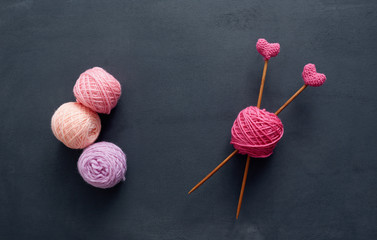 Pink knitting wool and knitting needles. Knitting needles with crochet pink hearts.