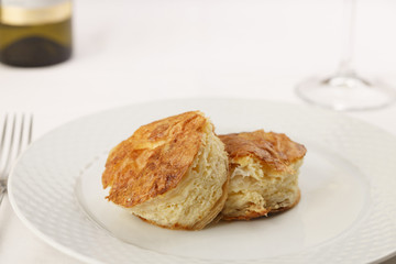Cheese puff pastry arranged on a plate, Wine bottle and wineglass in background, Traditional dish in elegant setting, Selective focus with soft light