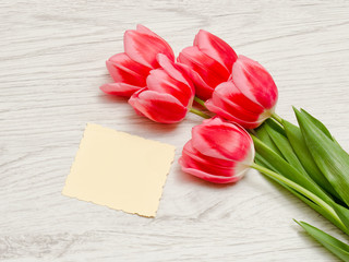 Clean card, pink tulips on a light wooden background. top view, space for text