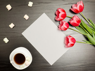 Clean sheet of paper, pink tulips and a mug of coffee. Black table. top view