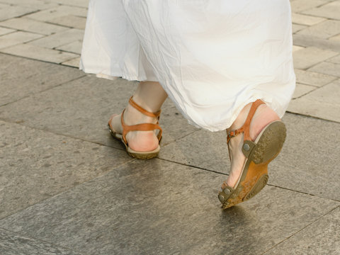 Feet Walking On The Sidewalk Girl In A White Dress And Sandals