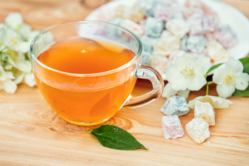 Cup of green tea with jasmine decorated with a turkish delight on wooden table