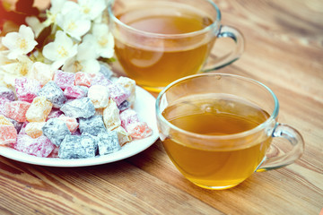 Two cups of green tea with jasmine decorated with a turkish delight on wooden table