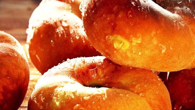 Wet ripe flat saturn peaches on a wooden table on a sunny summer day. 4K close-up pan shot