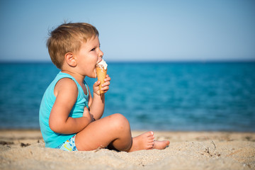 Sweet little child eating ice cream on beach, summertime