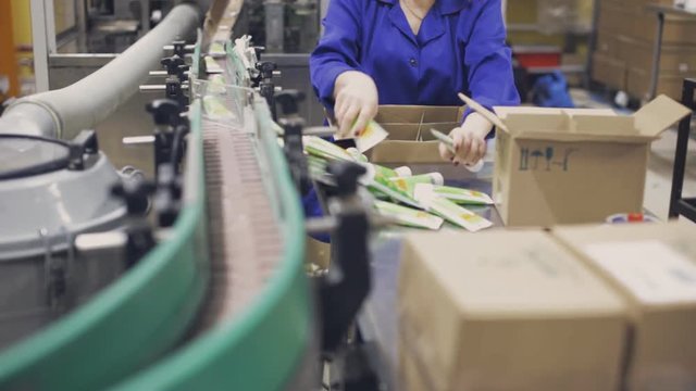 Woman at conveyor put the tubes in box