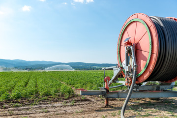 agricultural hose reel of a irrigation system with sprinkler in the background