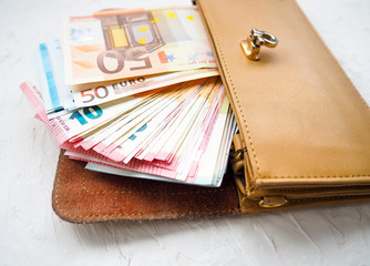 Euro money with brown wallet on the white table. Dealing with money.
