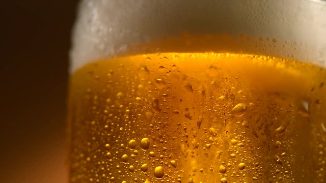 Cold beer in a glass with water drops. Craft beer close up. Rotation 360 degrees. 4K UHD video 3840x2160
