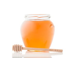 Glass jar full of honey and wooden stick on it isolated on a white background