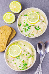 Delicious Greek chicken lemon soup on concrete background. 