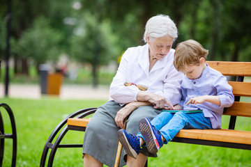Young boy and his great grandmother using tablet in park