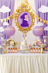Interior decoration for a child's birthday is one year in purple colors. Candy, macaroon, tiered cake, and juices.