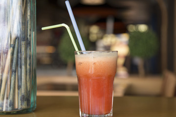 Fototapeta na wymiar Fruit cocktail glass in cafe or restaurant - selective focus point. Healthy orange organic juice 