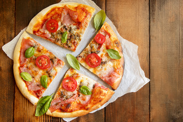 Pizza. Fresh Italian margherita with salami, basil and tomato on a  wooden table. Top view
