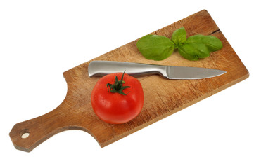 Feuilles de basilic, tomate et couteau posés sur une planche à découper 