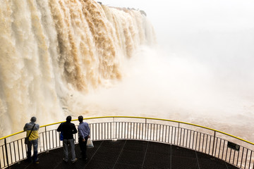 tourists in a platform at iguazu falls veiw from brazil