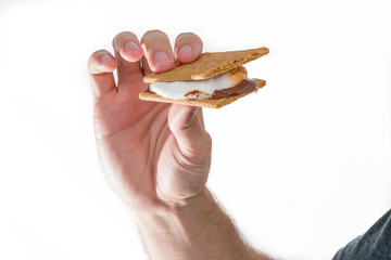 Male hand holding a s'more lit by a campfire isolated on white