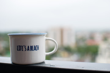 Coffee cup on steel beam, overlooking the city