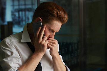 Serious man with cellphone making call home to say that he has much to do in office