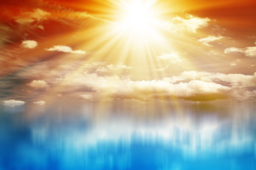 Fototapeta premium Kolorowy zachód słońca. Niebo z chmurami i słońcem nad błękitnym morzem