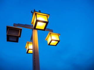Vintage electric light pole on walkway in park. Beautiful light in low light time.