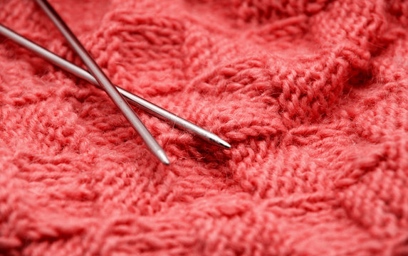 Detail of woven handicraft knit woolen design texture and knitting needle. Fabric red background