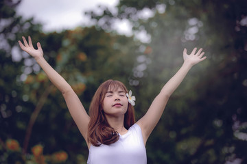 young woman standing in the park and show hands up to sky