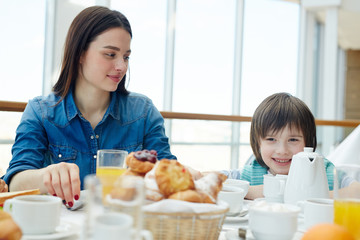 Happy boy and young woman eating breakfast