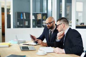 Businesman pointing at online data while explaining it to colleague