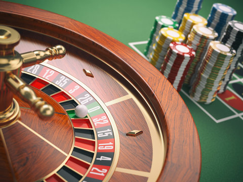 Casino roulette wheel with casino chips on green table. Gambling background.