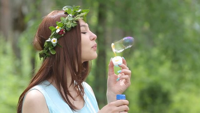 Beautiful girl blows soap bubbles