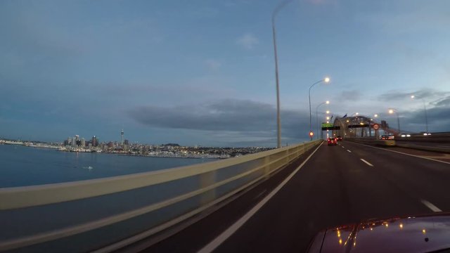 Car driving over Auckland Harbor Bridge at dusk.The bridge has an estimated capacity of 180,000 vehicles per day