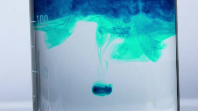 Close-up: chemical experiment and transformations inside a test tube or a chemical flask. A chemist or medical research scientist adds chemicals to a erlenmeyer flask for a violent chemical reaction.