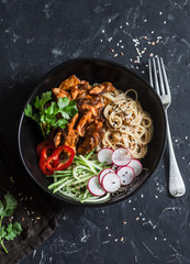 Rice noodles and teriyaki chicken stir fry with quick pickled cucumbers and radishes. On a dark background, top view. Asian food style