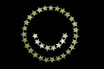 geometric circle of toy fluorescent glowing stars and and semicircle in the form of smiling faces on a black background