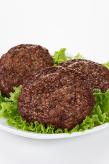 Roasted meatballs and lettuce leafs in white plate