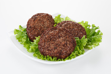 Roasted meatballs and lettuce leafs in white plate