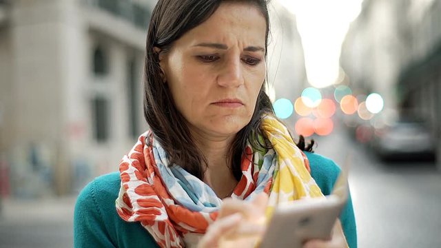 Woman checking smartphone in the city and looks dissatisfied, steadycam shot
