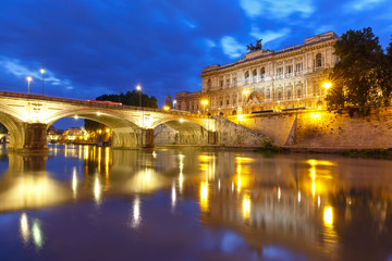 Fototapeta premium The Palace of Justice and bridge Ponte Umberto I with mirror reflection seen from the Tiber riverside during morning blue hour in Rome, Italy