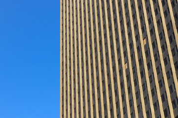 Fototapeta na wymiar Skyscraper against clear blue sky. Geometric pattern of windows with two imperfections