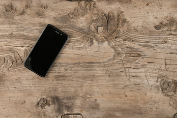 Blank screen mobile phone on wood background.