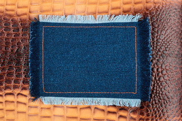 Frame made of denim with a fringe is on the brown crocodile skin, with space for your text.